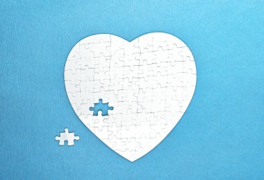White puzzles shape of heart on blue background. Health care concept