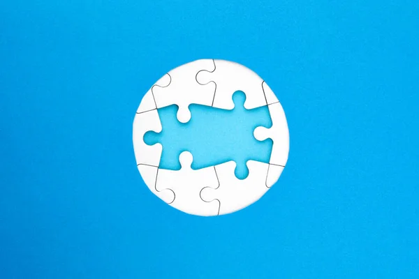 Frame of white puzzles on blue background. Place for your text. Mockup
