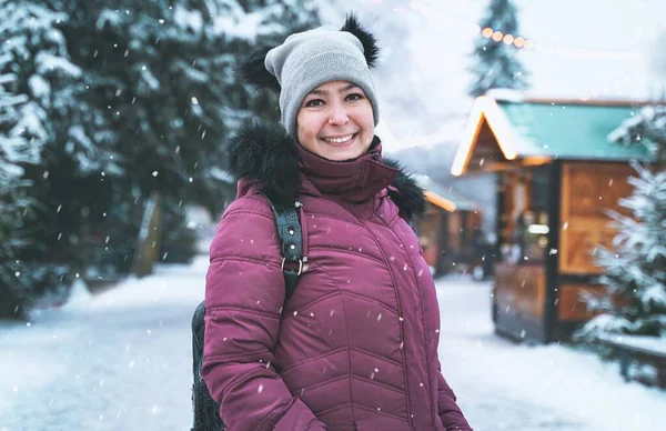 Brazilian woman with beautiful smile on background of a snowy winter. Positive pretty girl in outerwear outdoors. Portrait of ordinary person
