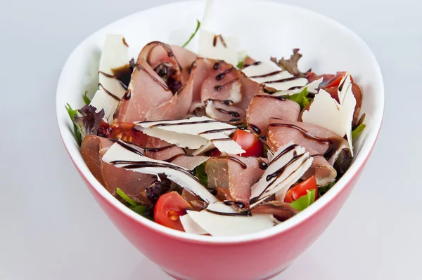 Fresh salad with prosciutto and vegetables on a white background — Stock Photo, Image