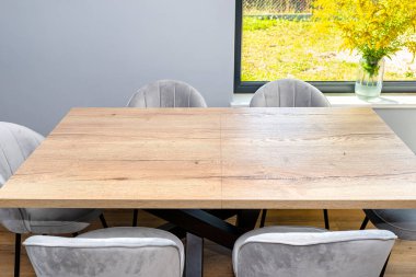 Oturma odasına ve mutfağa bağlı modern bir yemek odası duvarda büyük pencereler, görünür bir masa ve sandalyeler var..