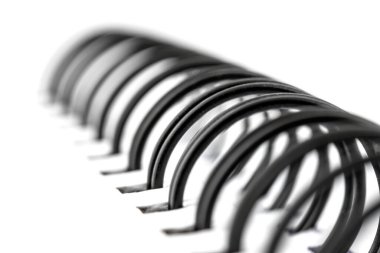 Sayfaları birbirine bağlayan siyah metal spiralli beyaz bir defterin makro fotoğrafı..