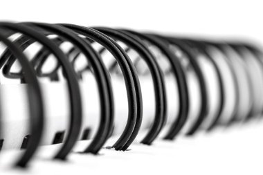 Sayfaları birbirine bağlayan siyah metal spiralli beyaz bir defterin makro fotoğrafı..