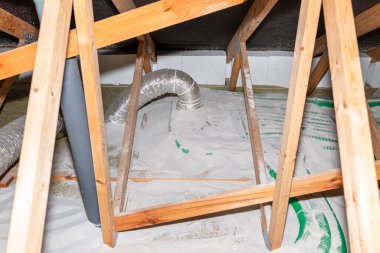 Pipe insulation with expanded perlite in domestic ventilation with energy recovery, a visible system of green pipes spread over the roof trusses.