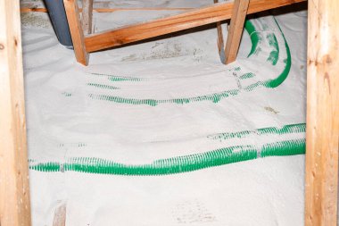 Pipe insulation with expanded perlite in domestic ventilation with energy recovery, a visible system of green pipes spread over the roof trusses.