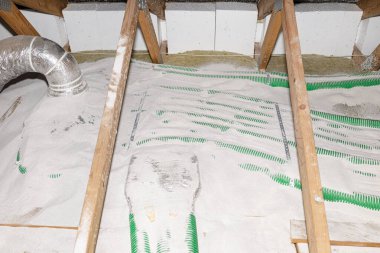 Pipe insulation with expanded perlite in domestic ventilation with energy recovery, a visible system of green pipes spread over the roof trusses.