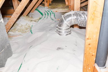 Pipe insulation with expanded perlite in domestic ventilation with energy recovery, a visible system of green pipes spread over the roof trusses.