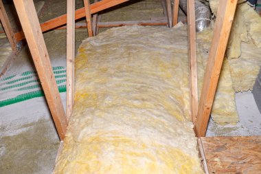 Expanded perlite and mineral wool insulation laid on pipes in domestic ventilation with heat recovery, green pipes laid on the roof truss.