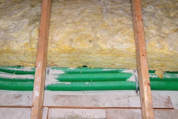 屋根トラス上に敷設された熱回収 緑のパイプと国内換気パイプに敷設されたパーライトとミネラルウール断熱材の拡大 — ストック写真