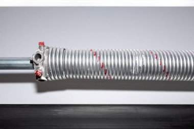 Springs tensioning the garage door mechanism, visible red spring and spring head.