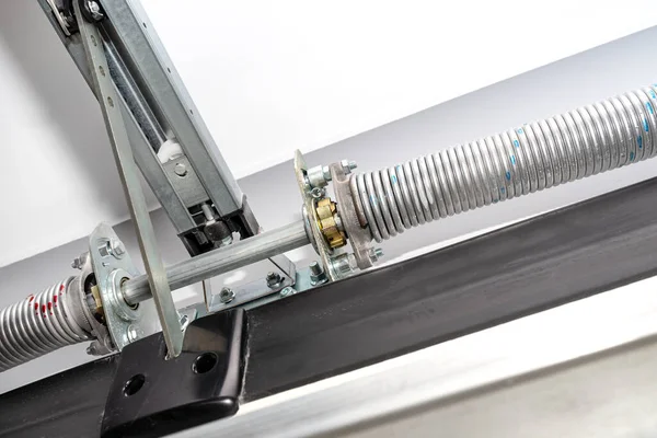 Springs tensioning the garage door mechanism, view from the inside, visible rail with chain and spring protection.