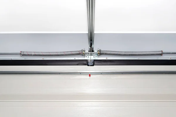 Springs tensioning the home garage door mechanism, view from the inside, visible disconnection of the electric drive.