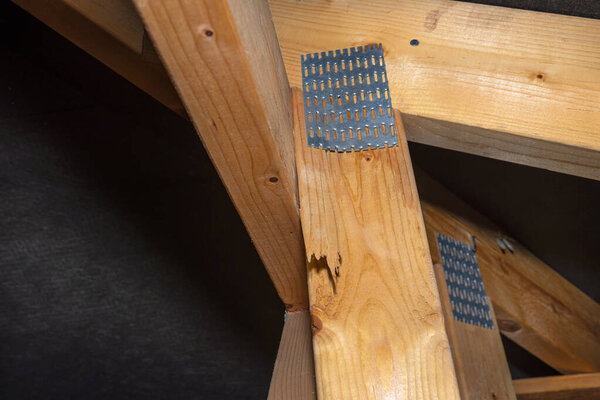 Поврежденная колючая пластина, соединяющая конструкцию крыши, покрытую мембраной, на односемейном доме, видимая поврежденная ферма.