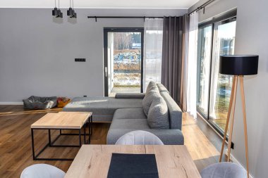 Gri kanepesi, büyük verandası ve masaları olan modern ve basit bir oturma odası..