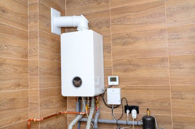 Doğal gaz için modern bir gaz kazanı, seramik fayanslarla kaplı bir kazan dairesine yerleştirilmiş..