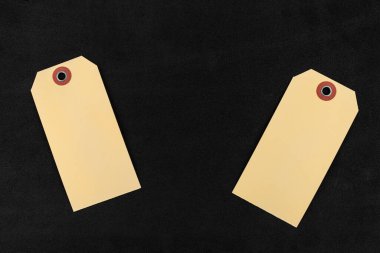 Yan tarafında süngerden siyah bir zemin üzerinde duran iki boş kahverengi hediye etiketi var..