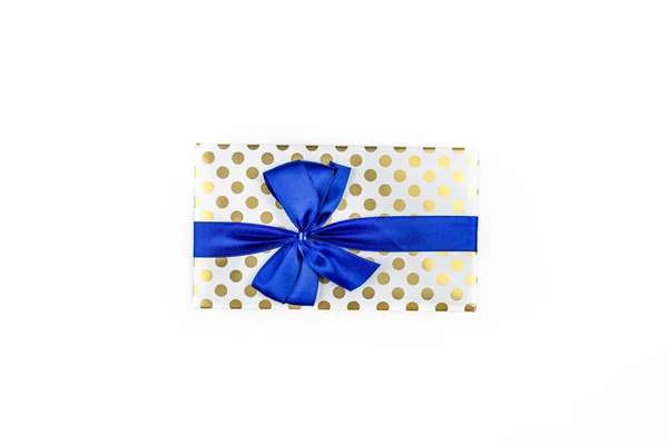 一种用白纸包裹的礼物 用蓝色带子包着金圆 用蝴蝶结捆着 用白色的背景隔开 顶部看 — 图库照片
