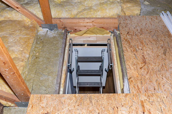 Скользящая металлическая лестница на чердак в потолке, открытая клапан и развернутая лестница, современный вид. Вид сверху лестницы вниз
.