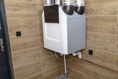Modern bir gaz kazan dairesinde duvarda asılı duran ısı giderici ile ev mekanik havalandırma. Kahverengi seramik fayanslar ahşabı taklit ediyor..