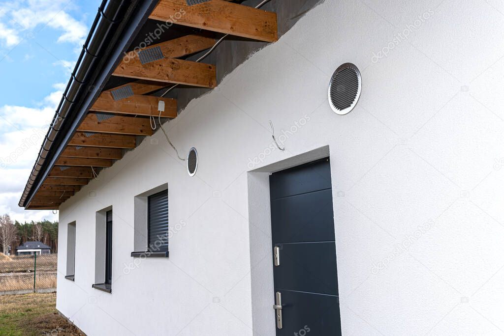 Air intake and exhaust in the wall of a single family house for mechanical ventilation with heat recovery, secured with a metal grill with mesh.