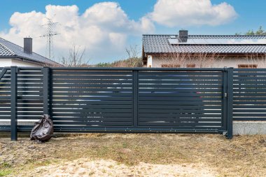 Modern antrasit panel çitler, garaja açılan açık kapı, bahçenin manzarası..
