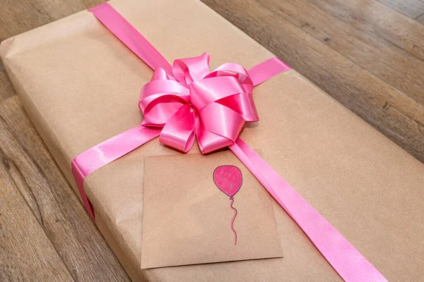 弓で結ばれたピンクのリボンで包まれたグレーの紙に包まれた贈り物 封筒の上に描かれた風船 — ストック写真