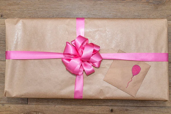 弓で結ばれたピンクのリボンで包まれたグレーの紙に包まれた贈り物 封筒の上に描かれた風船 — ストック写真