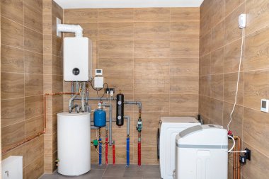 Seramik fayanslarla kaplı modern bir gaz kazan dairesi ahşabı taklit eder, çamaşır makinesi ve su yumuşatıcısı olan tam teşekküllü kazan dairesi ekipmanları görünür..
