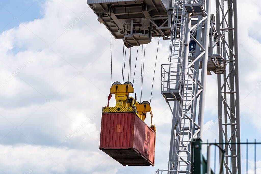 A container gantry crane on a rail loads the container into a barge standing on the banks of the river Rhine in Germany.
