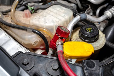 Arabanın vanasına R134a soğutucusunu doldurmak için klima sisteminden kırmızı bir kısa devre bağlantısı kuruluyor..