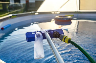 Cleaning the home pool in the garden with a brush, cleaning and maintenance of the home pool.