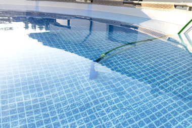 Cleaning the home pool in the garden with a brush, dragging dirt from the bottom of the pool.
