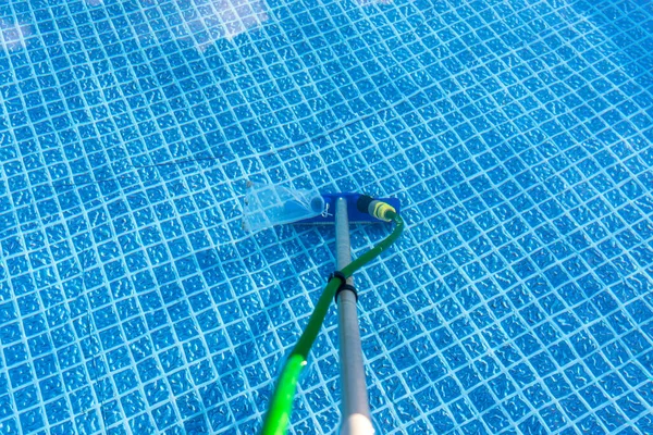 Cleaning the home pool in the garden with a brush, dragging dirt from the bottom of the pool.