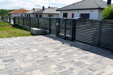Antrasit renginde modern bir çit garaja açılan görünür bir sürgülü kapı ve posta kutusu olan bir kale..