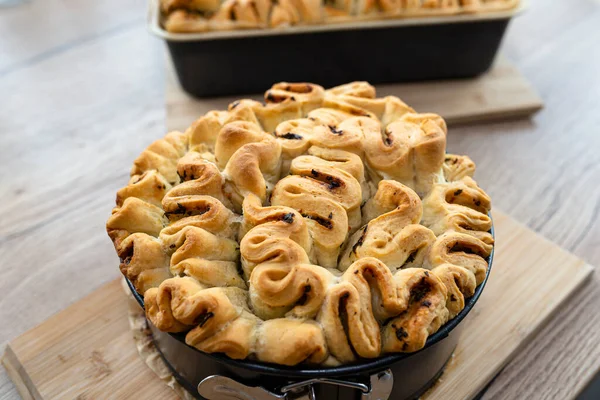 Homemade rectangular and round bread with garlic butter and herbs, in a baking tin.