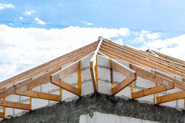 Roof trusses not covered with ceramic tiles on a single-family house under construction, visible roof elements and rafters.