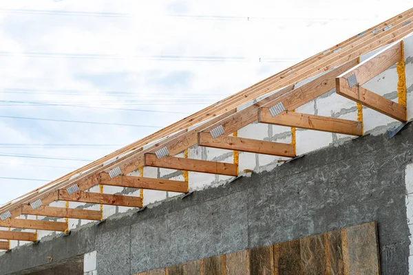 Roof trusses not covered with ceramic tiles on a single-family house under construction, visible roof elements and rafters.