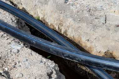 Plastic water pipe lying along the ditch with high groundwater, water connection in the housing estate.