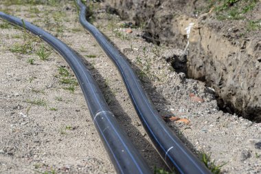 Plastic water pipe lying along the ditch with high groundwater, water connection in the housing estate.