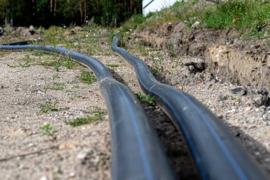 Plastic water pipe lying along the ditch with high groundwater, water connection in the housing estate.