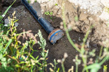 Closed end of a plastic water pipe lying along a ditch with high groundwater, water connection on the estate.