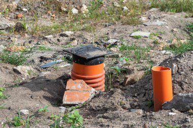 Inspection of the sewage system with a closed cast iron manhole, visible plastic pipes.