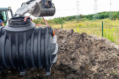 Installation of a single-chamber home sewage treatment plant, the excavator raises the tank.