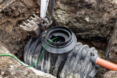 Installation of a single-chamber home sewage treatment plant, the excavator raises the tank.