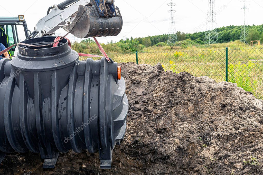 Installation of a single-chamber home sewage treatment plant, the excavator raises the tank.