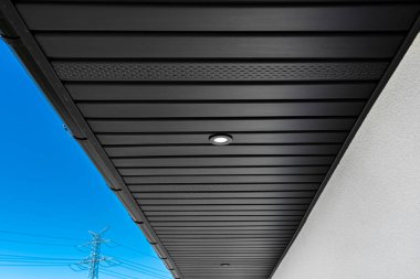 Çağdaş bir grafit çatı astarı kirişlere bağlanmış, LED ışıkları açık..