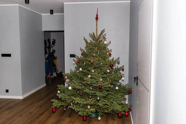 Ένα Έλατο Χριστουγεννιάτικο Δέντρο Διακοσμημένο Μπιχλιμπίδια Στέκεται Στην Αίθουσα Ενός — Φωτογραφία Αρχείου