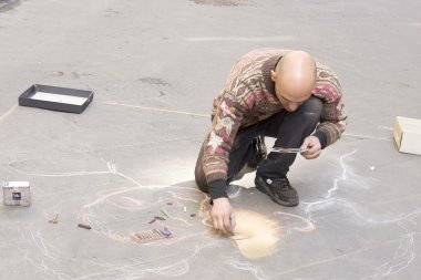 utcai művész fest egy képet a járdán