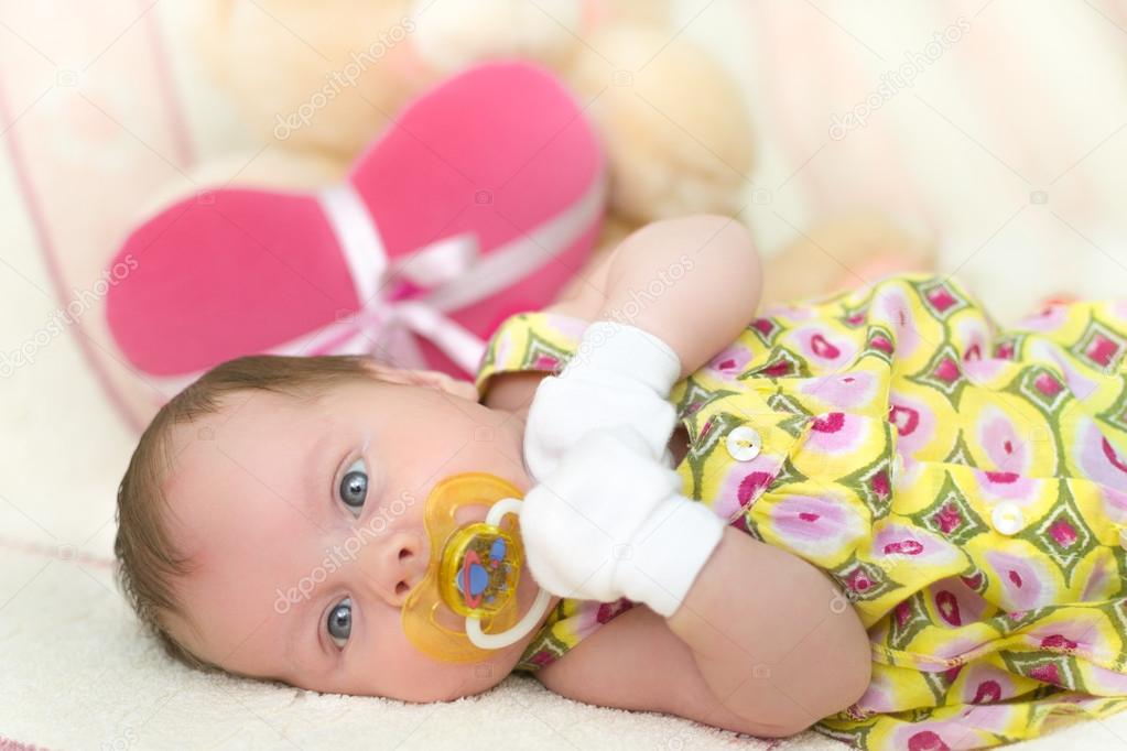 Infant baby girl lying on bed with teddy bear