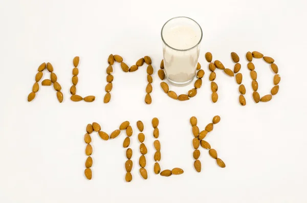 Almond milk and several almonds on a white background — Stock Photo, Image